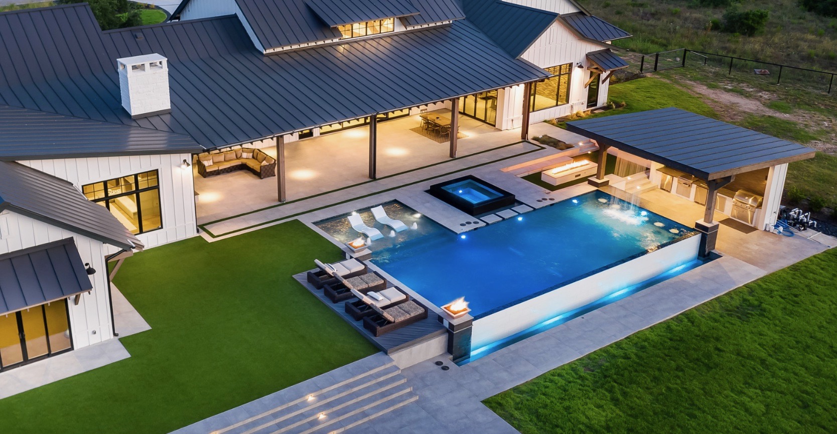 Aerial dusk view of a modern farmhouse with an infinity pool