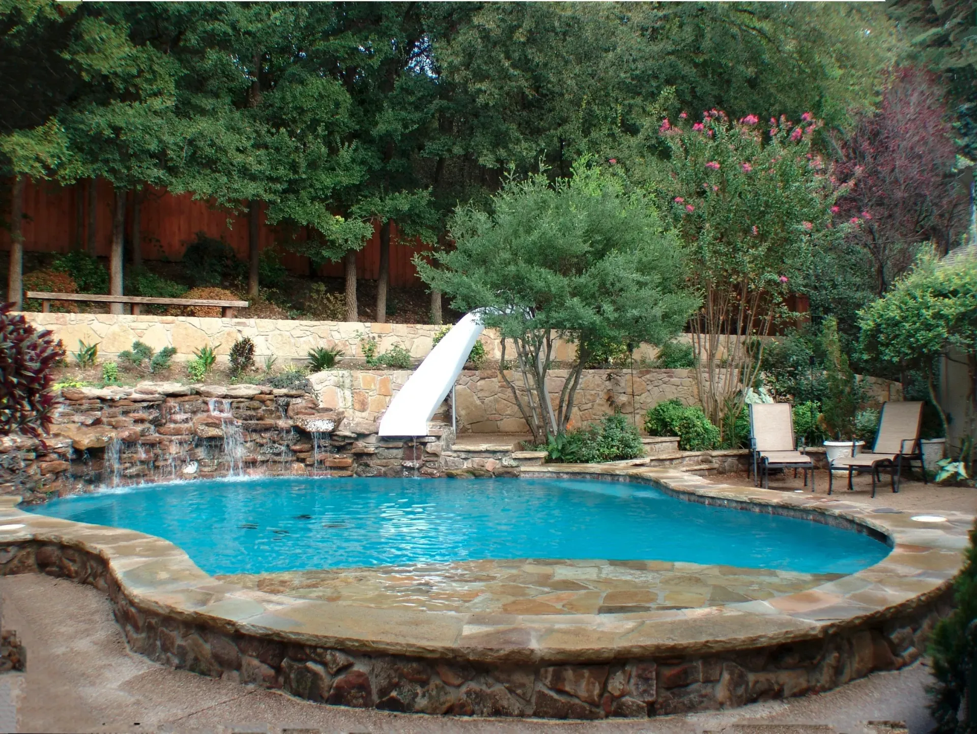 Freeform pool with a slide and waterfall at a suburban home