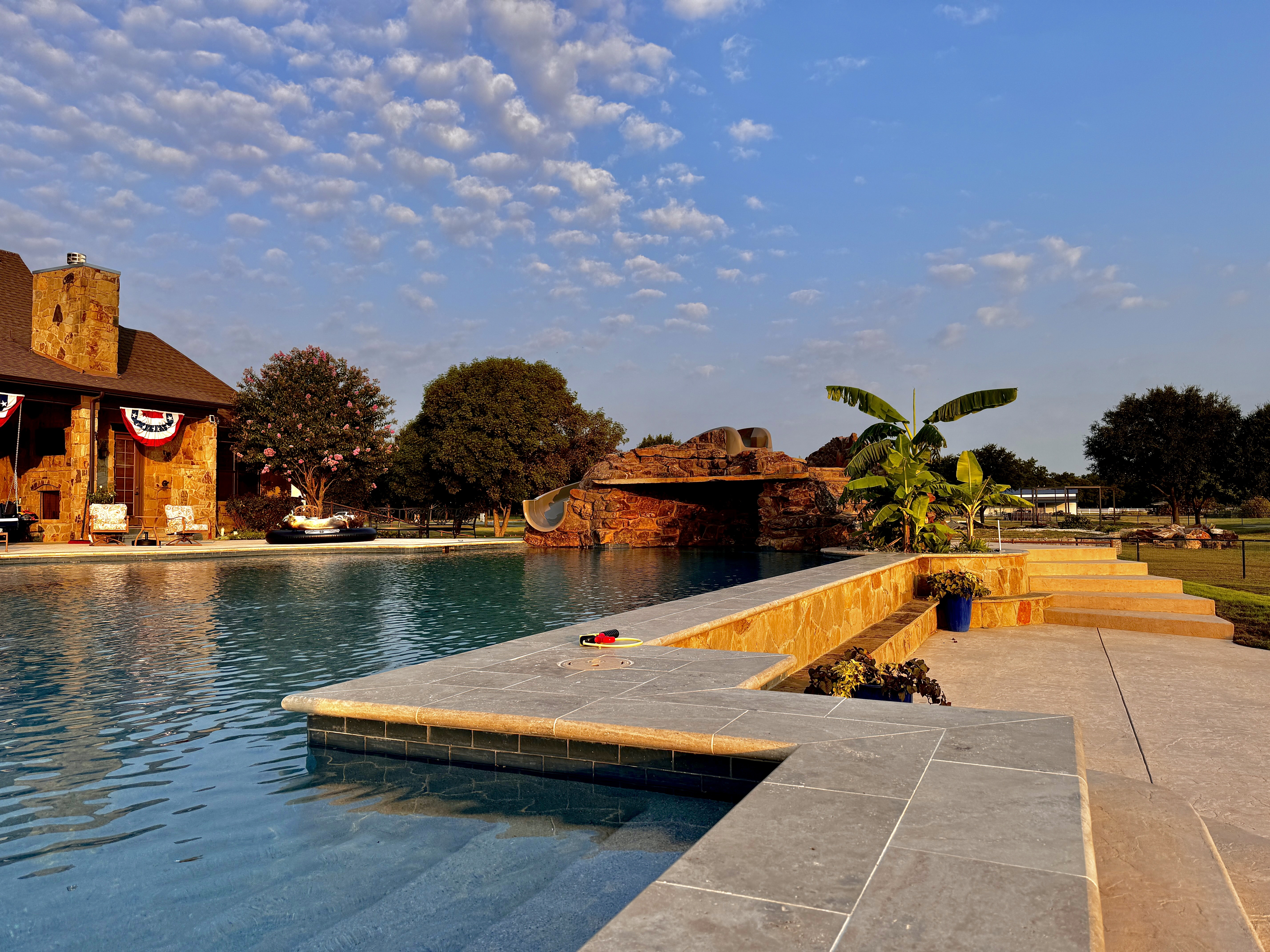 Large pool with a rock grotto and travertine decking