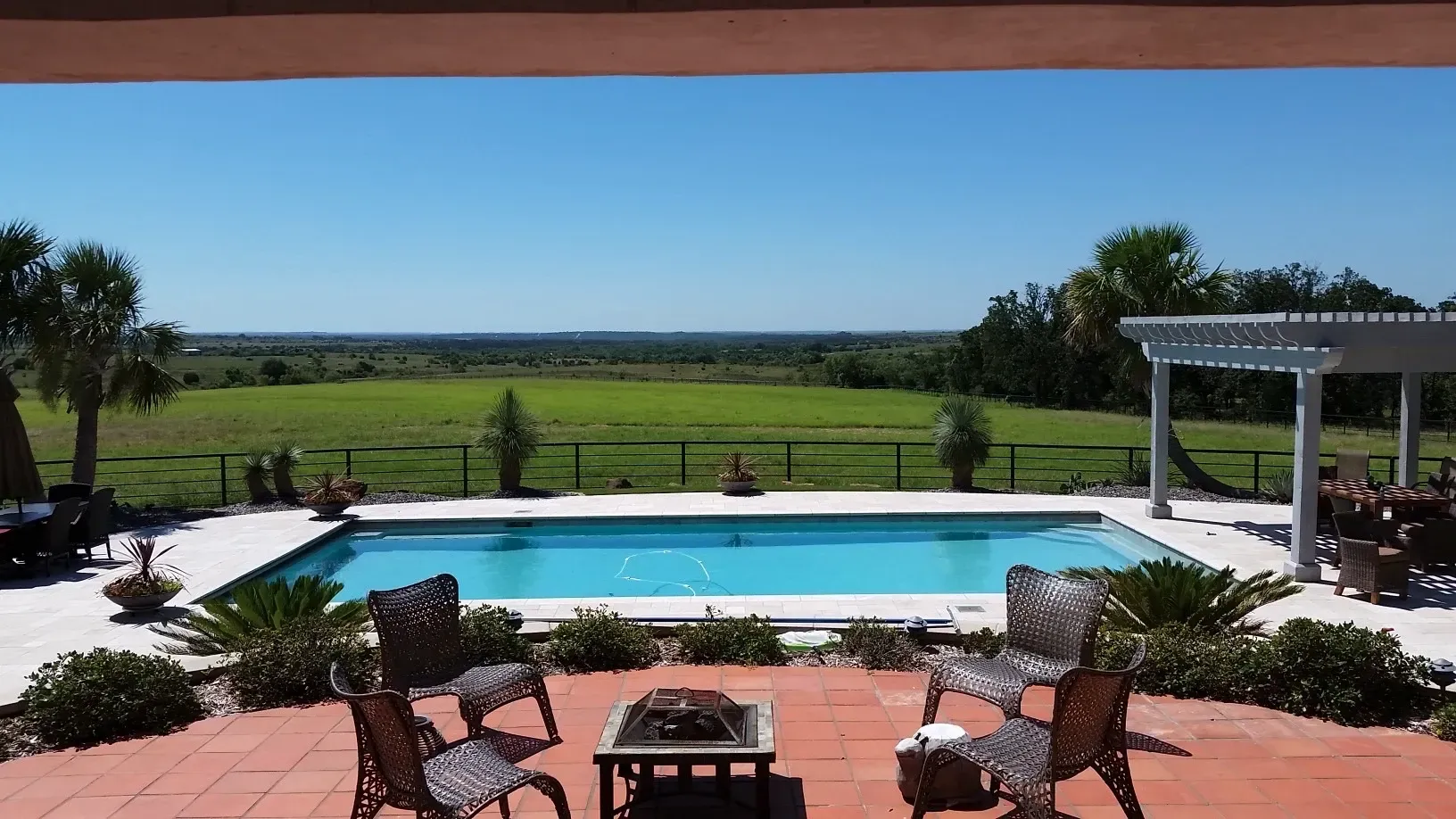 Pool with an open countryside view, palms and a pergola