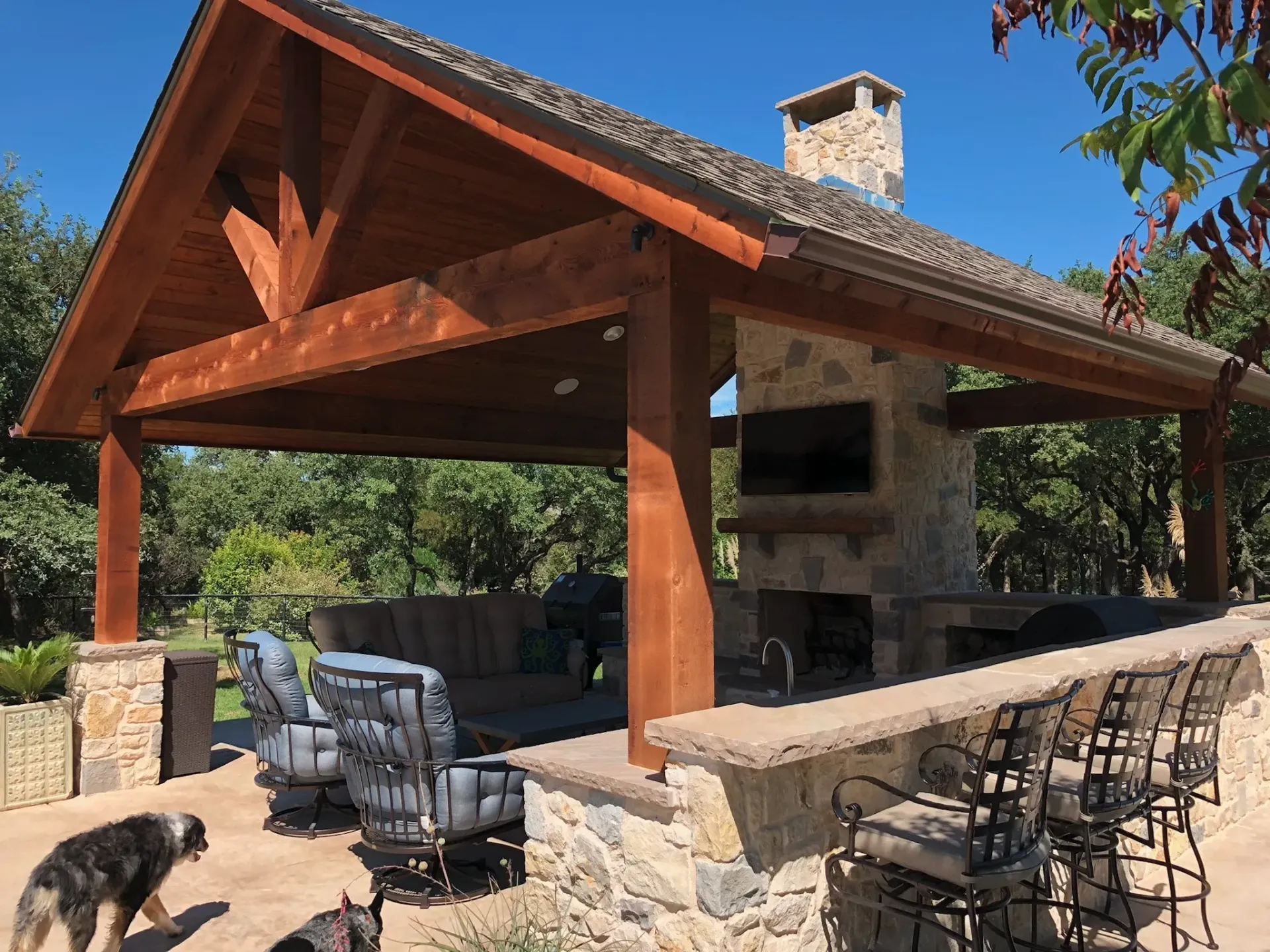 Outdoor pavilion with a stone fireplace and full outdoor kitchen