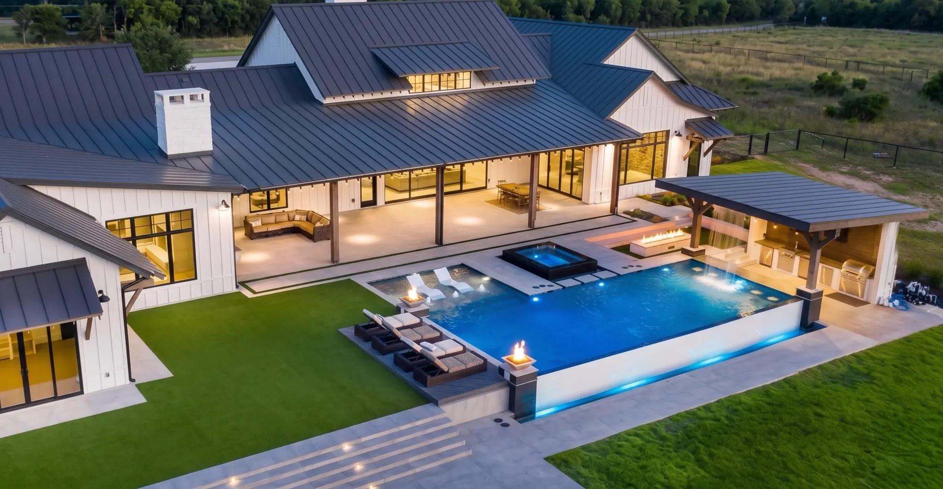Aerial dusk view of an infinity pool with fire bowls