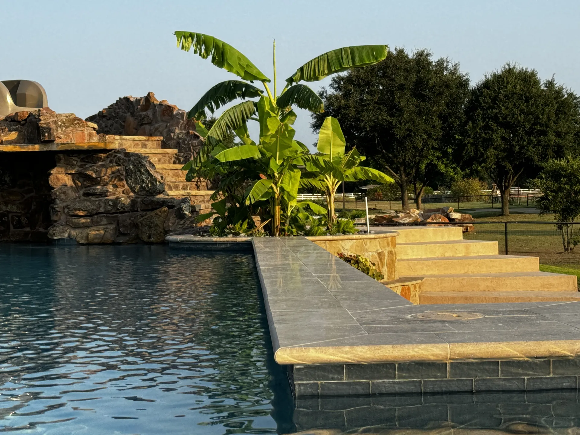 Pool edge with a rock grotto and banana trees