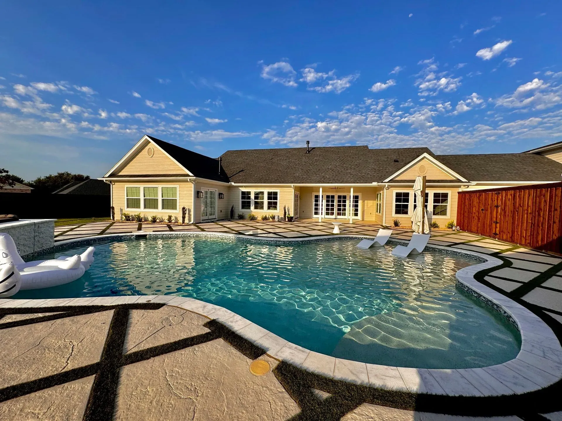 Freeform pool with chaise loungers at a suburban home