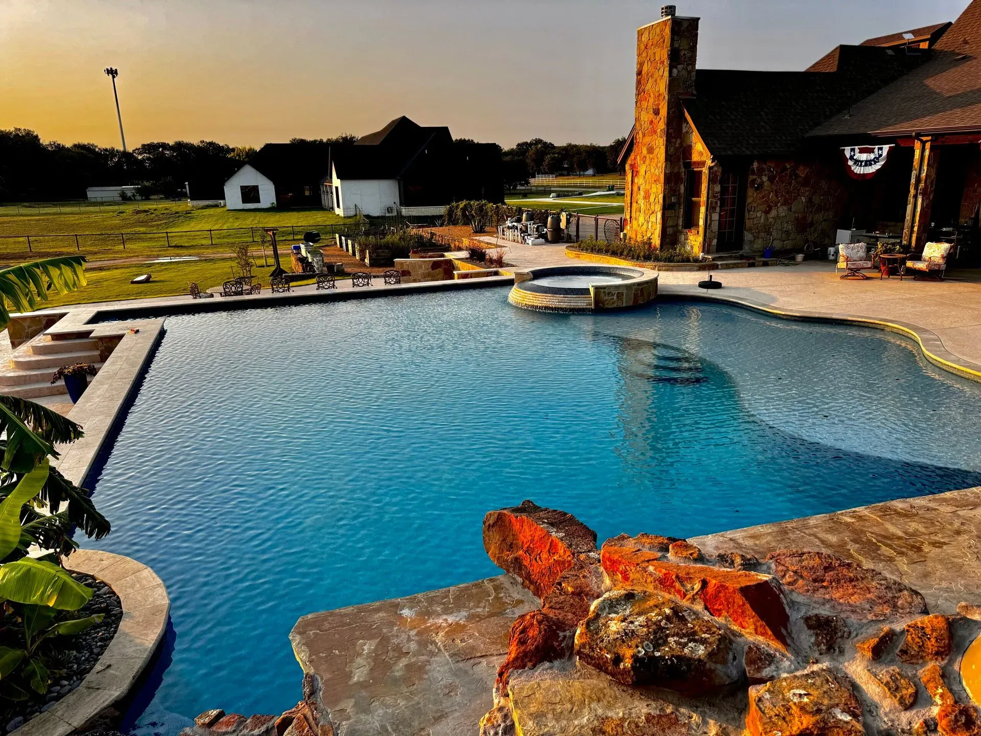 Freeform lagoon pool with a rock grotto, slide and tropical landscaping