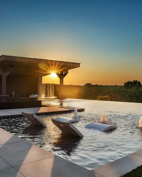 Infinity-edge pool with in-water loungers at golden hour