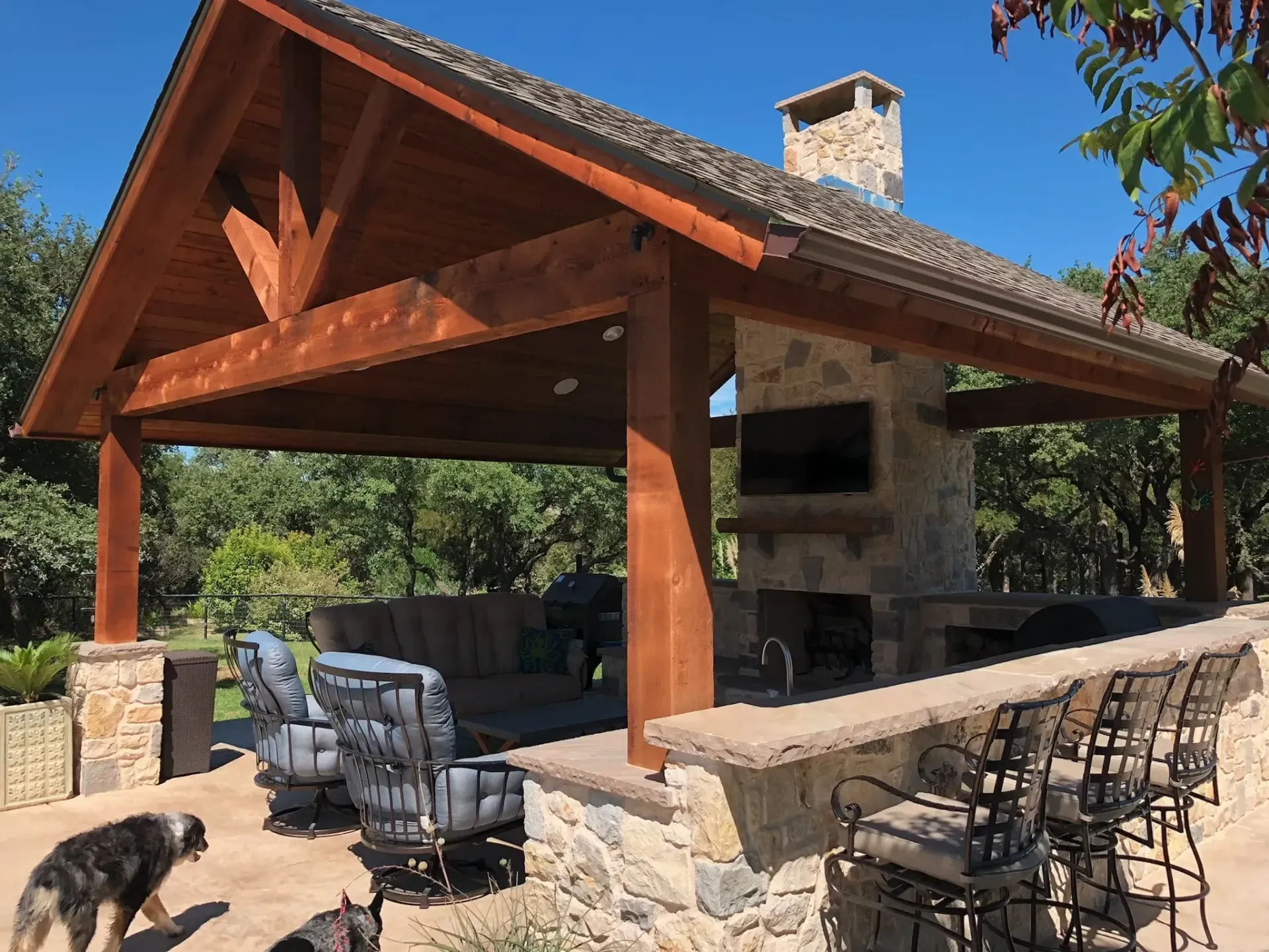 Outdoor pavilion with a stone fireplace and kitchen